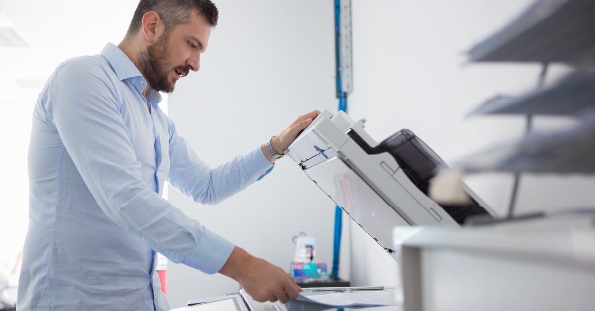 An employee scans a document in an unsecured printing environment, where a forgotten document could pose a significant liability..