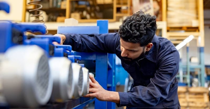 A worker at a pump manufacturing plant examining products.
