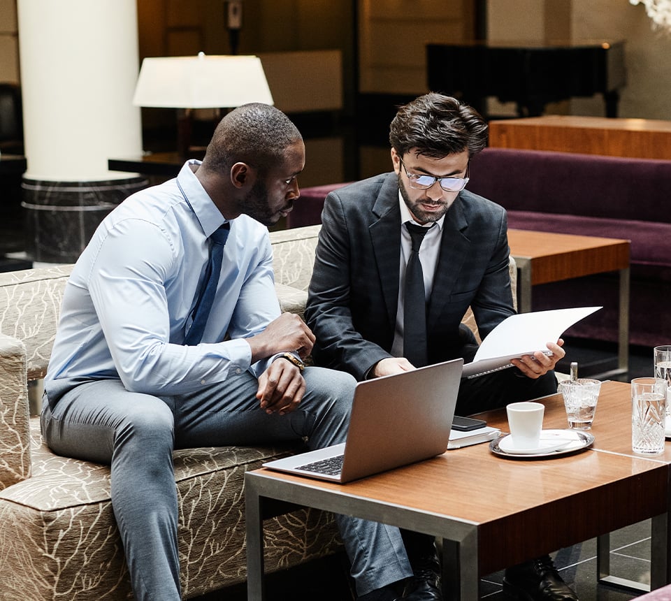 Two individuals sharing notes and a laptop