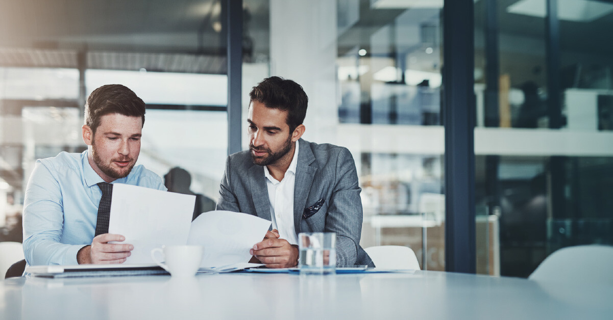 Two executives look over an agreement on paper.