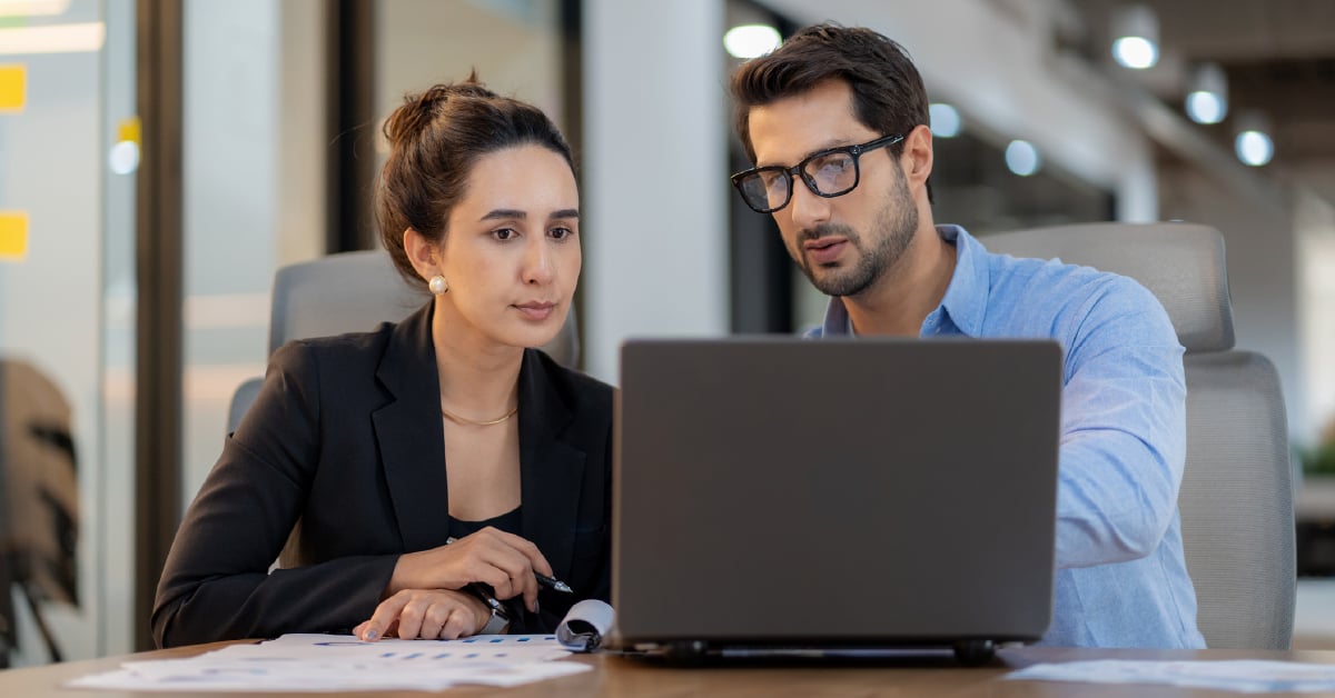 Two business leaders explore what their incident response plan should include, in front of an open laptop. 