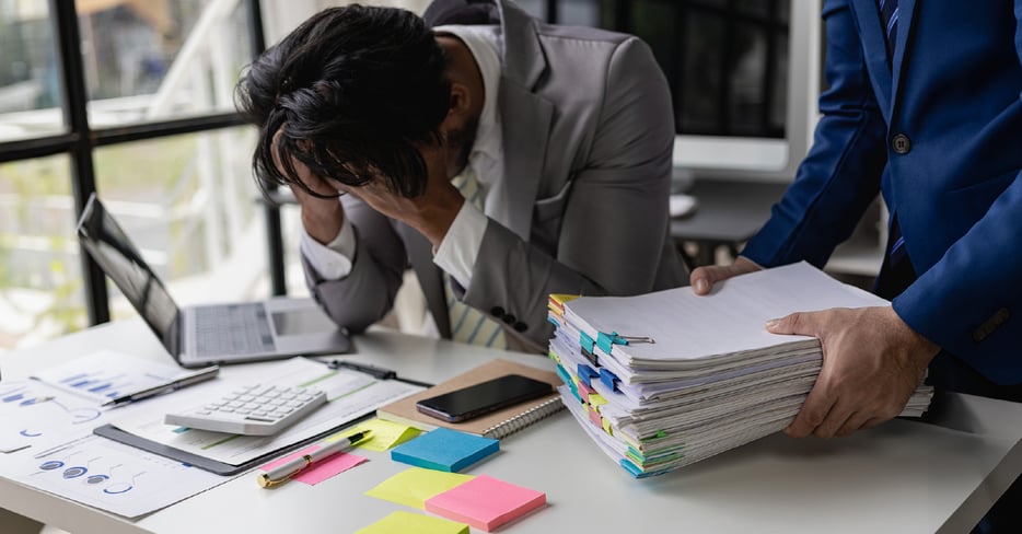 Frustrated employees with a stack of paperwork. 