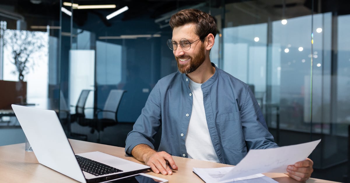 A male employee tracks print costs in order to reduce printing expenses in his business.