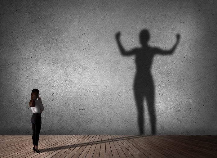 Shadow of a professional woman flexing against backdrop
