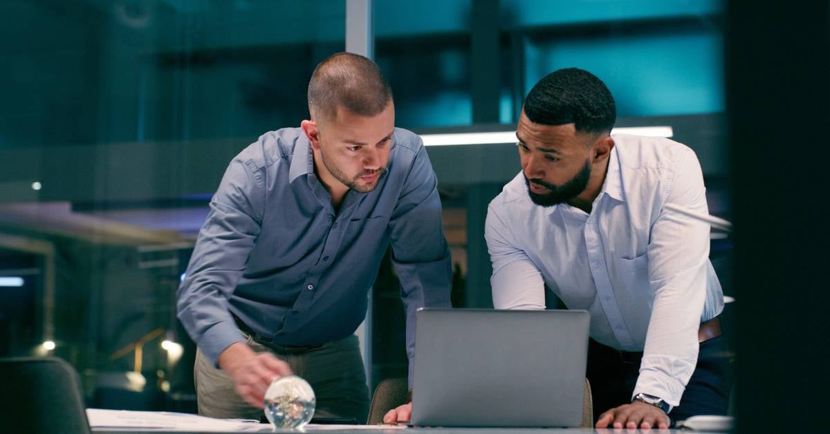 Twoi IT workers look at data on a laptop. 